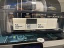 Printed two-colour labels clipped to the front of a Bambu Lab AMS 2 Pro, reading PLA Translucent, PLA+ Black and PLA Jade White